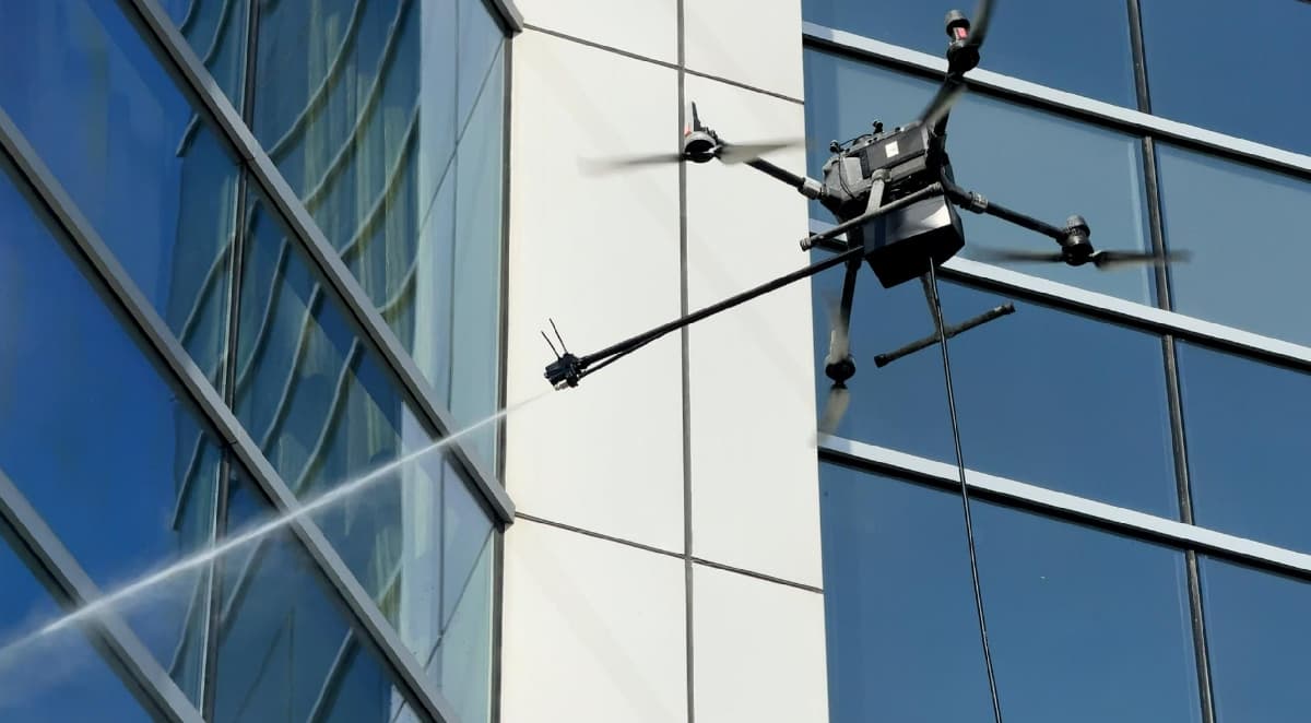 Drone window cleaning service in action – modern cleaning drone washing high-rise building glass Drone window cleaning service in action – modern cleaning drone washing high-rise building glass