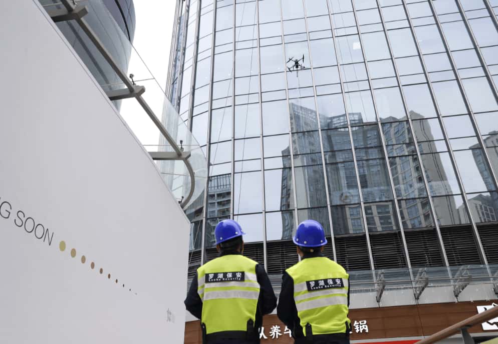 Drone window cleaning service in action – modern cleaning drone washing high-rise building glass Drone window cleaning service in action – modern cleaning drone washing high-rise building glass