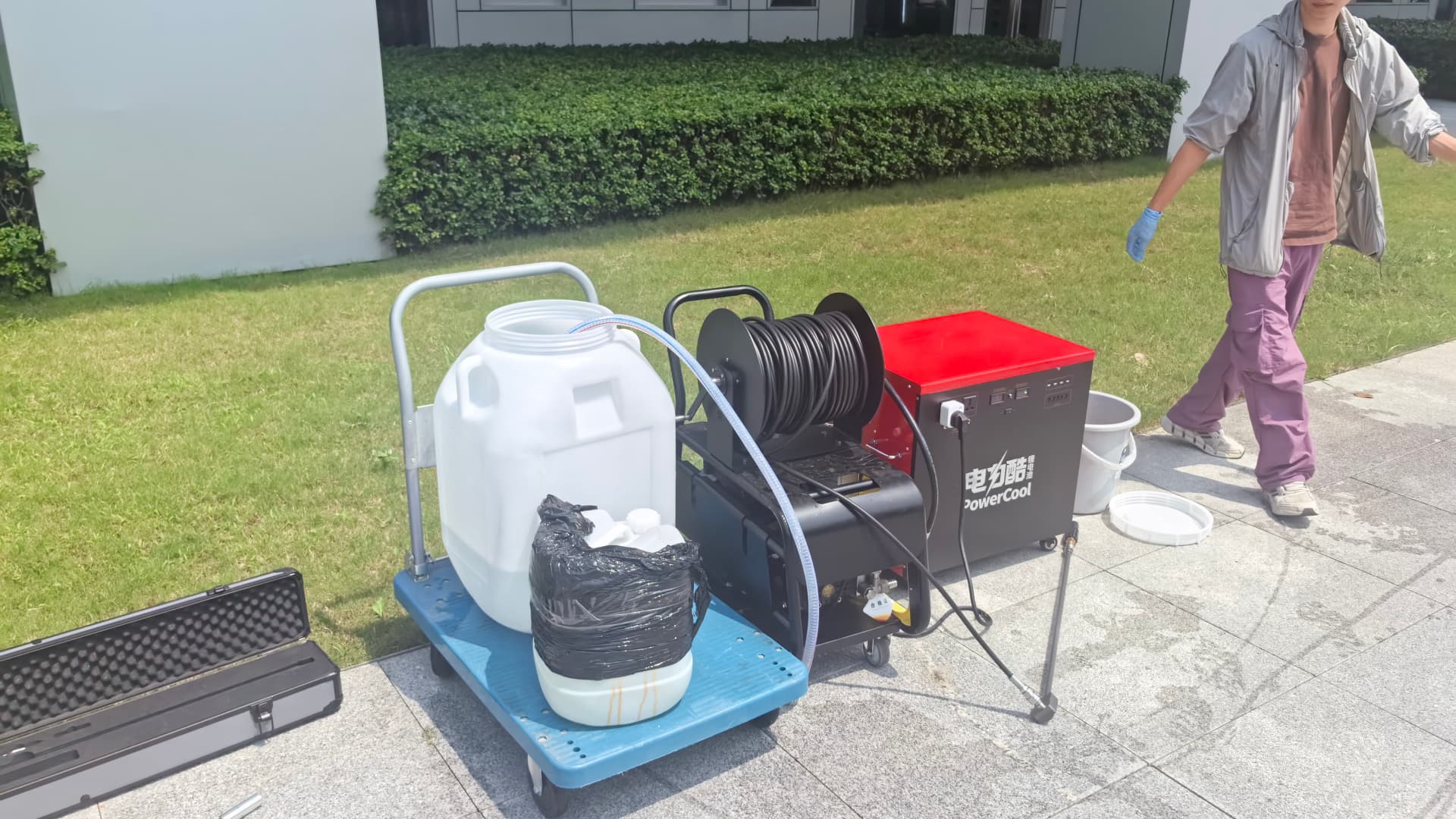 Cleaning drone spraying a high-pressure water fan along a tall glass curtain wall tower Cleaning drone spraying a high-pressure water fan along a tall glass curtain wall tower