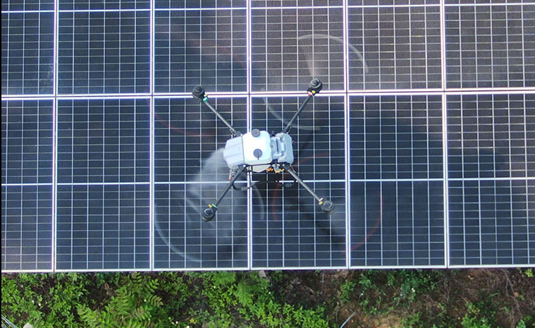 Drone spraying water over a solar panel array at a ground-mounted PV plant Drone spraying water over a solar panel array at a ground-mounted PV plant
