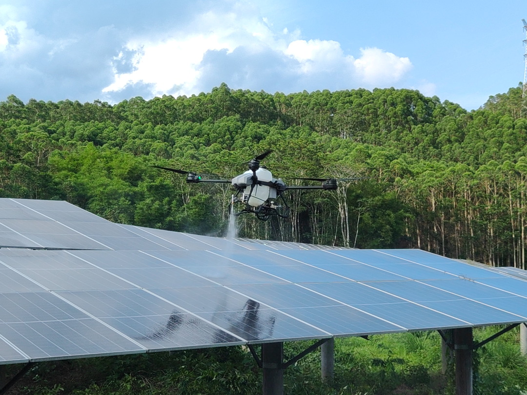 Drone spraying water over a solar panel array at a ground-mounted PV plant Drone spraying water over a solar panel array at a ground-mounted PV plant