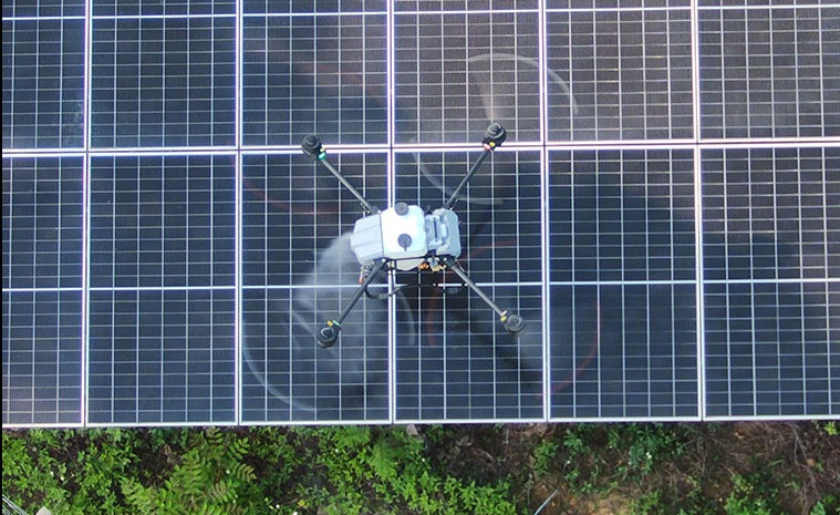 Drone spraying water to clean a dusty solar panel array Drone spraying water to clean a dusty solar panel array
